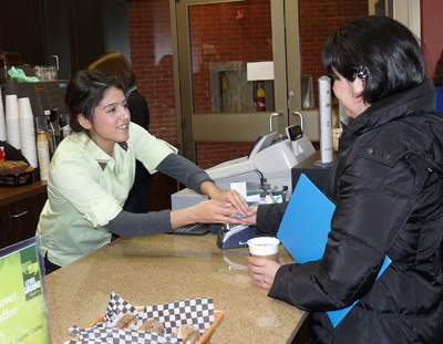 Barista serving a customer at By the Books.